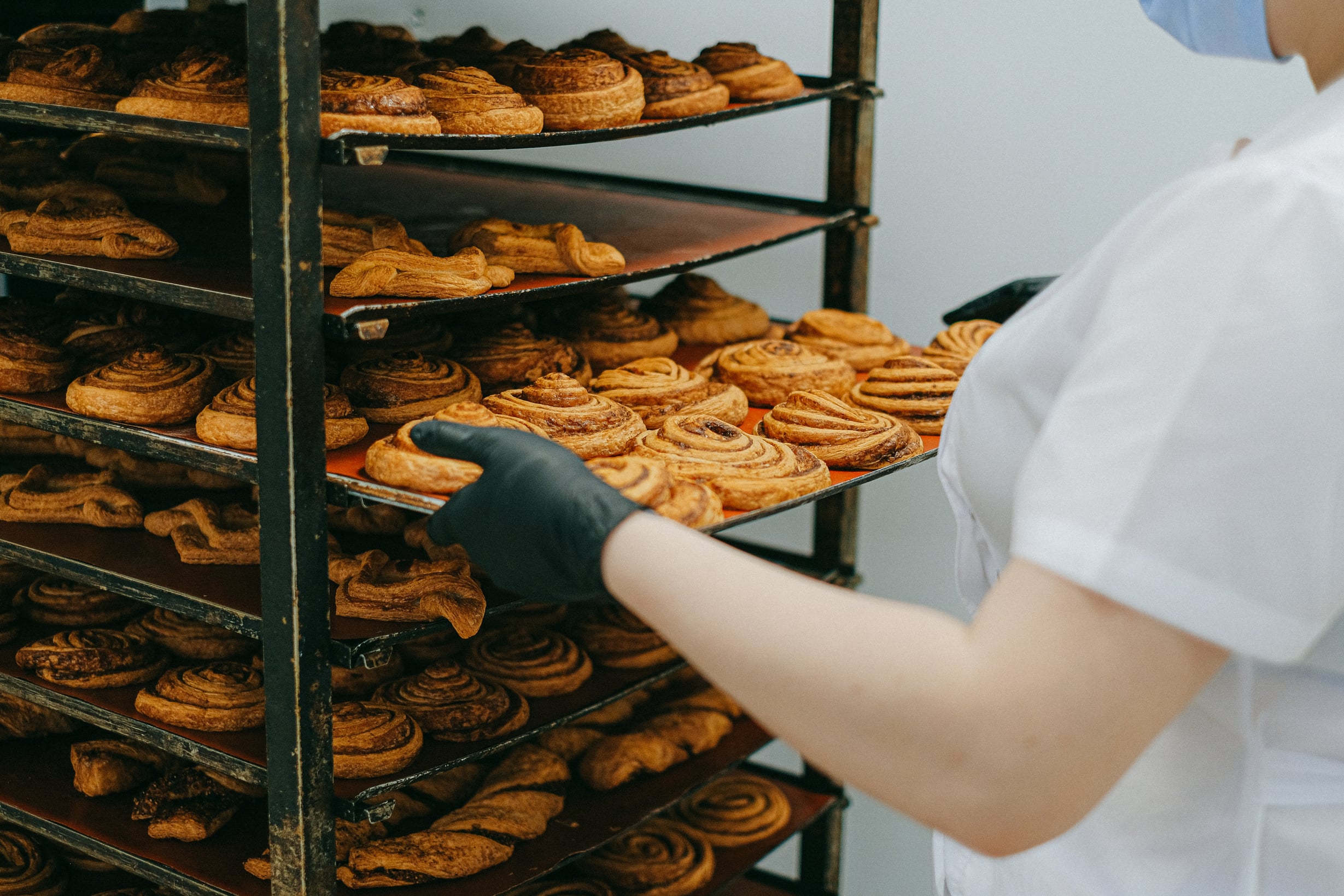 Photo of a Person Taking Out a Tray of Cinnamon Rolls